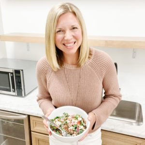 Tanya is shown holding a salad in front of her office kitchen.